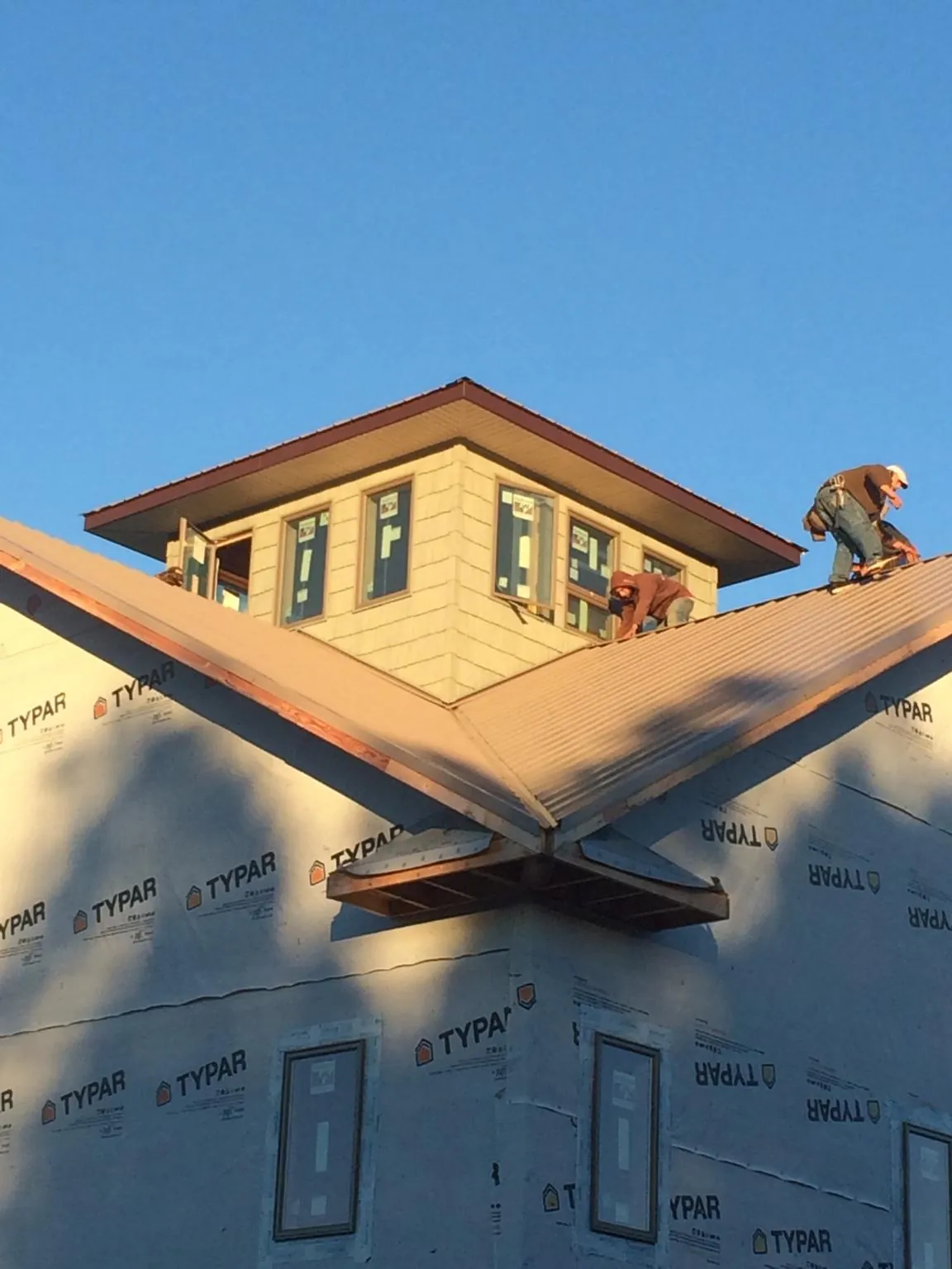 Roofers working around a rooftop cupola on a new metal roof at sunset — Roof Waterproofing in Blue Ridge by Roofing Brothers